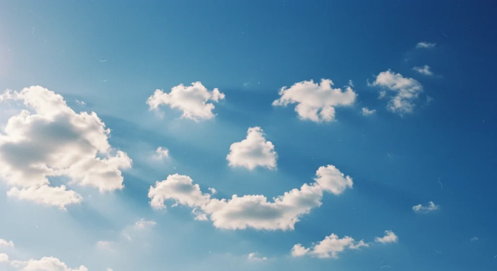 Clouds forming a distinct smiley face in a blue sky, illustrating the universal recognition of facial expressions signalling happiness or positive emotion